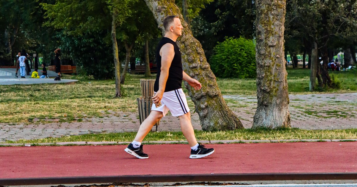 Hombre adulto caminando por la pista de un parque al atardecer